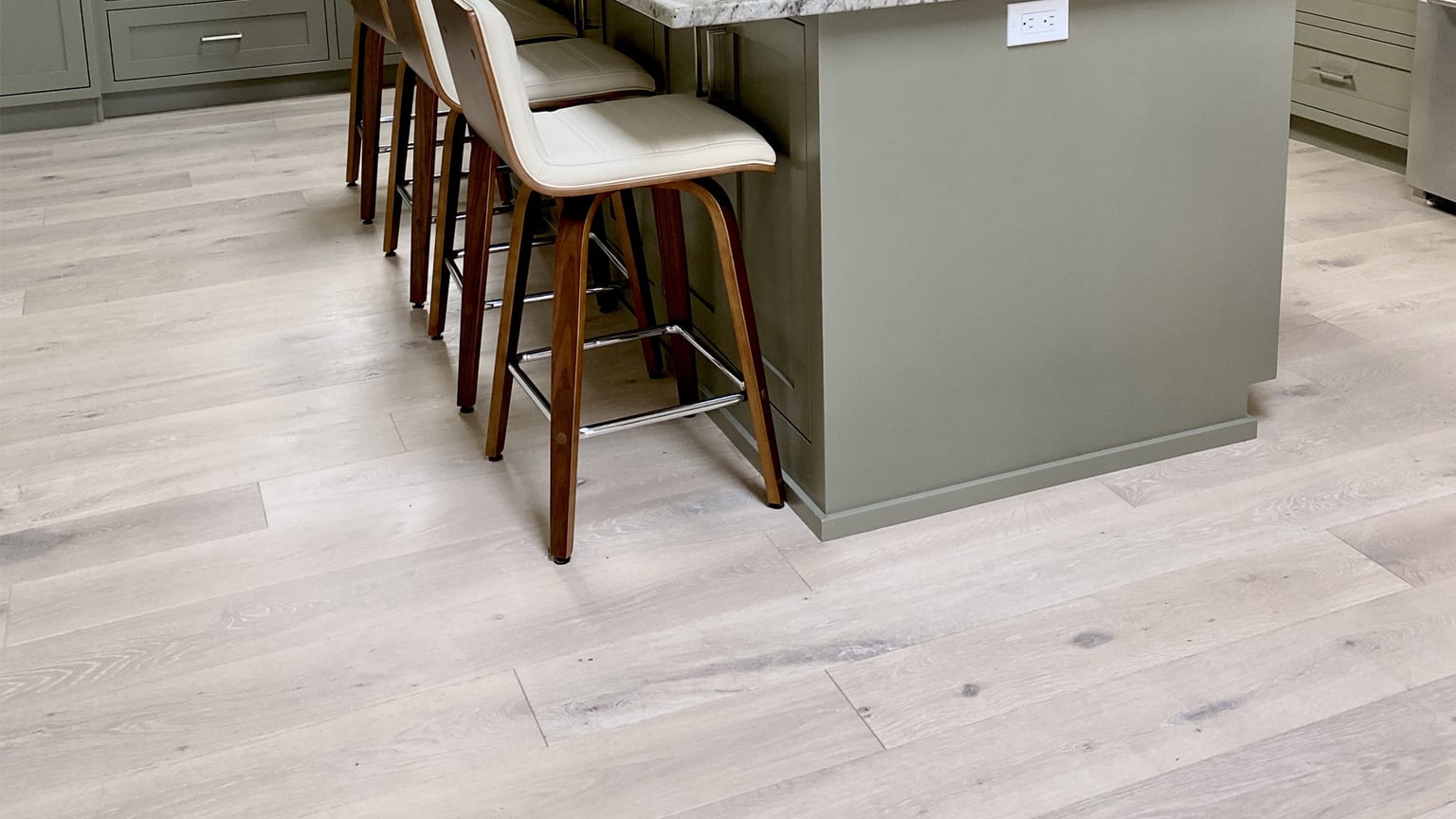 Pale Monarch Plank Lago Como oak planks in a kitchen with a sage green island and walnut stools