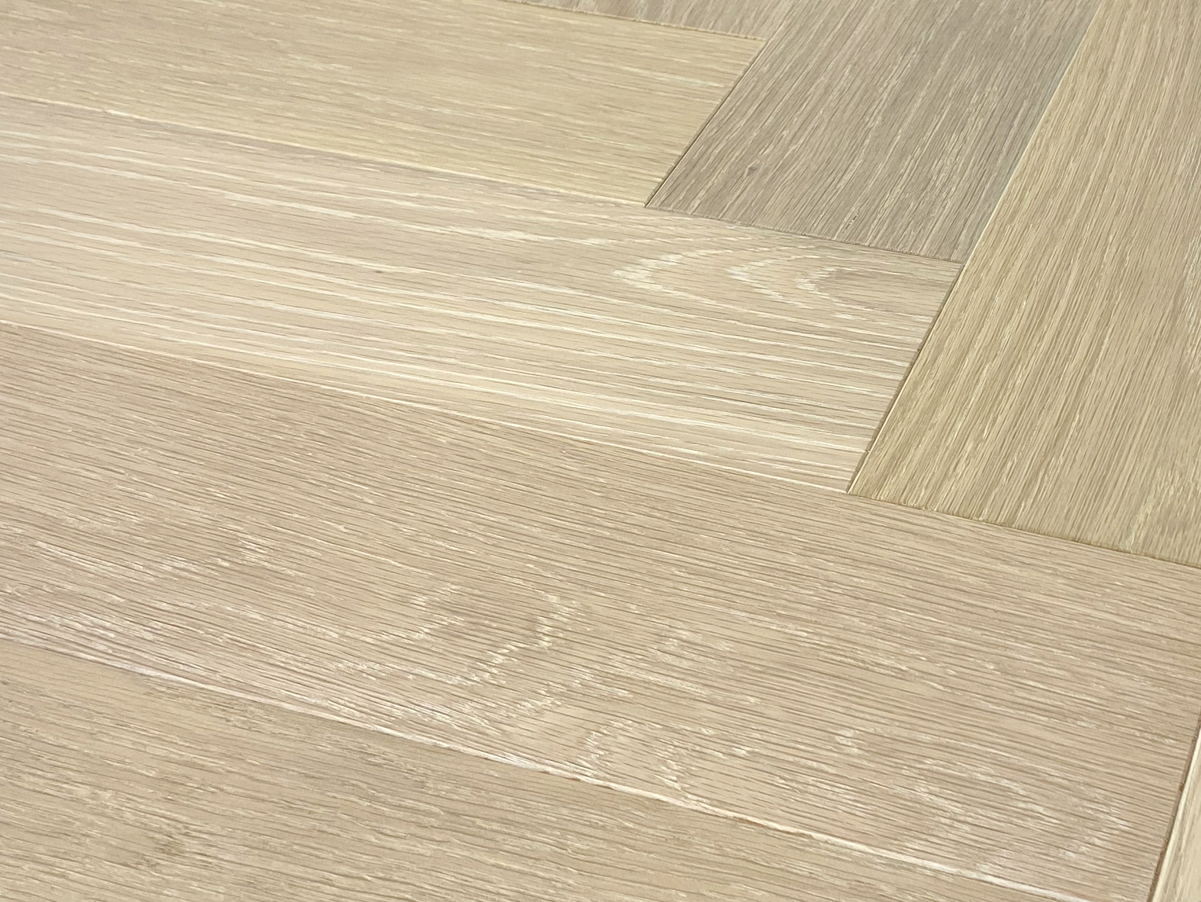 Wire-brushed oak in a herringbone angle shot with strong limed grain through the middle rows