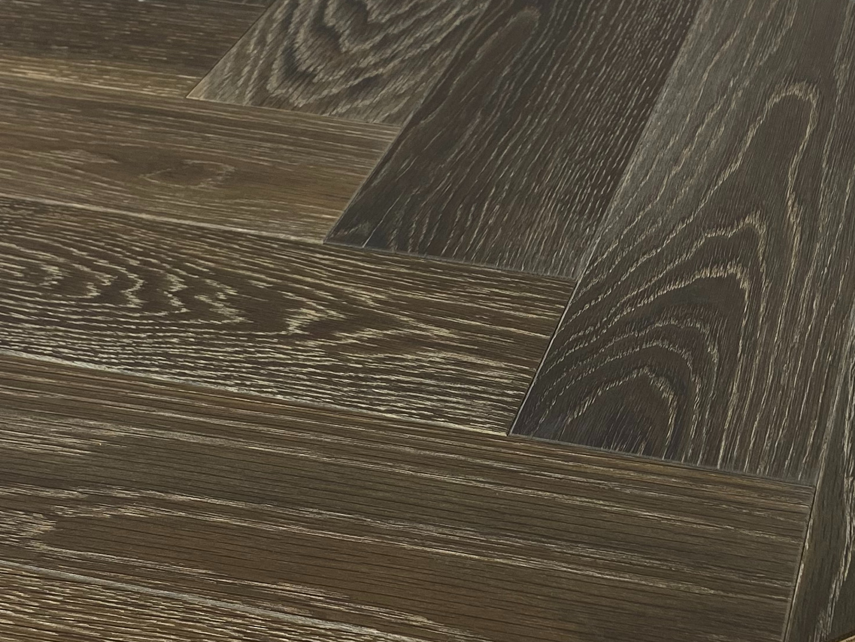 Dark wire-brushed oak in a low angle close-up with white filled pores across the grain