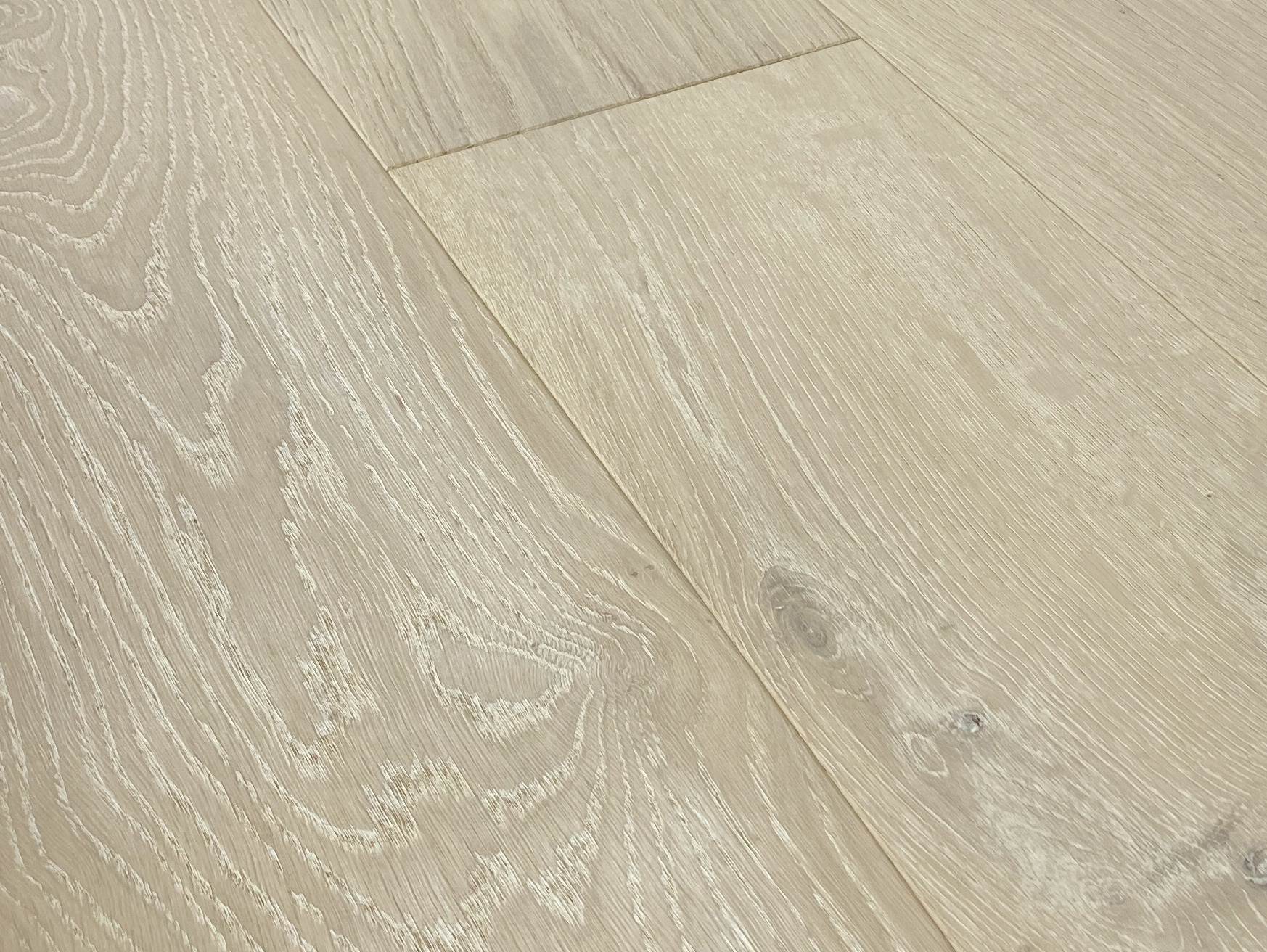 Low angle close-up of pale oak planks with open grain and an end joint near the top