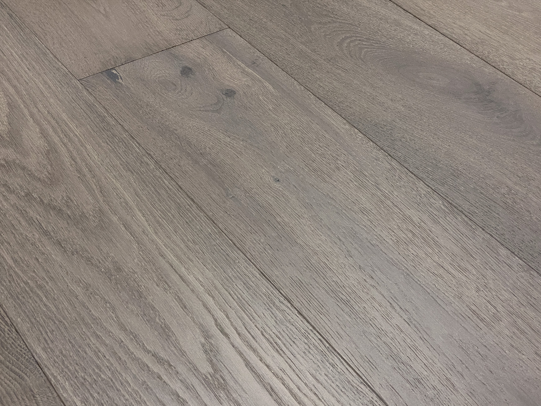 Sharp plank close-up with an end joint and dark knots, in a cool grey tone under flat light