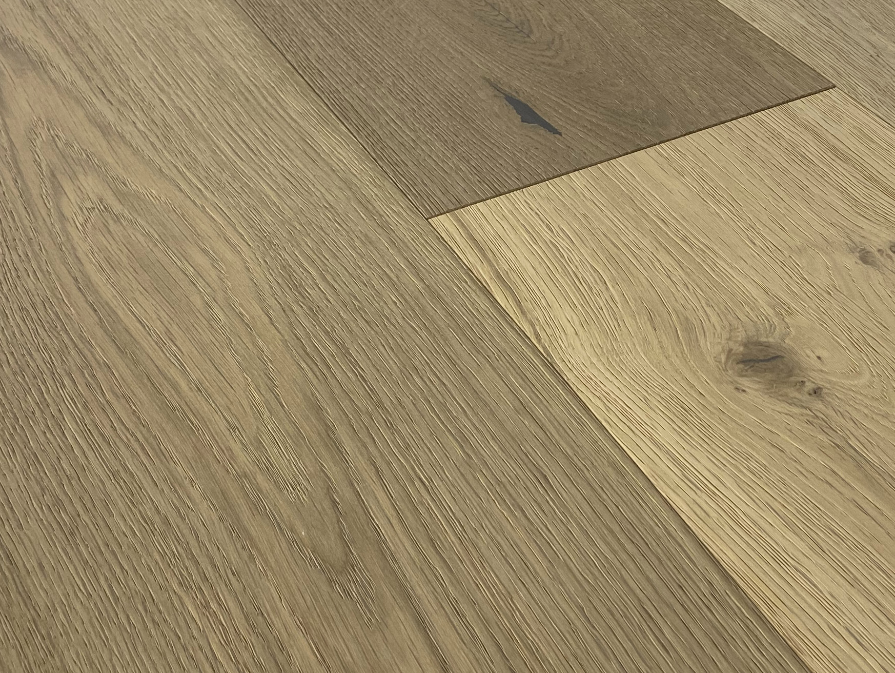 Low close-up of brushed oak grain, a dark filled knot and an end joint between two planks